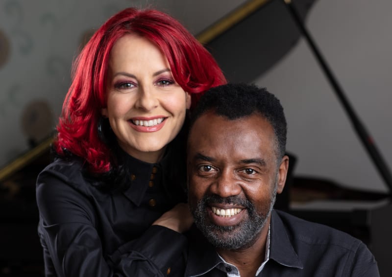 Carrie and David sitting together smiling into the camera.