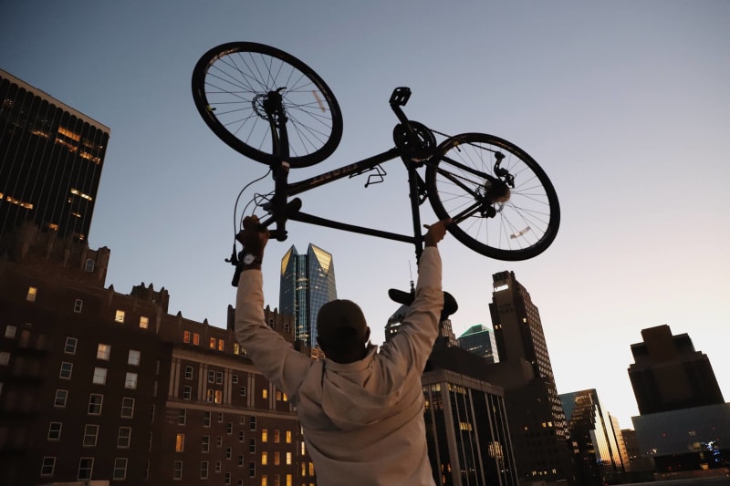 A Wheels Project recipient holding his bike up toward the sky